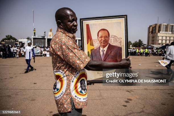 Supporter of holds a portrait of Burkina Faso's ousted president Blaise Compaore during a campaign rally of Burkinabe presidential candidate for the...