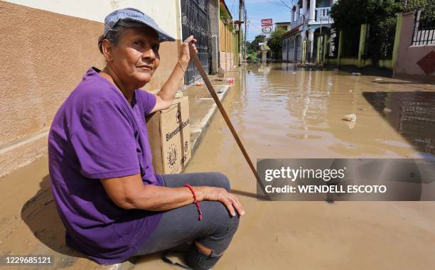 Woman sits on the sidewalk in the flooded municipality of La Lima near San Pedro Sula in Honduras, on November 19 after heavy rains from Hurricane...