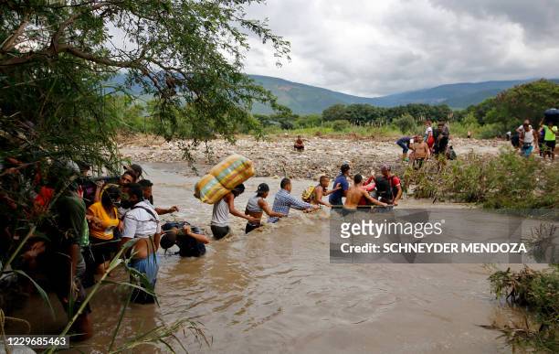 Migrants use a rope to cross the Tachira river, the natural border between Colombia and Venezuela, as the official border remains closed due to the...