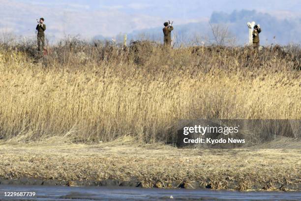 Photo taken Nov. 13 from Dandong, a Chinese border city by the Yalu River, shows soldiers installing barbed wire on a river bank in North Korea's...