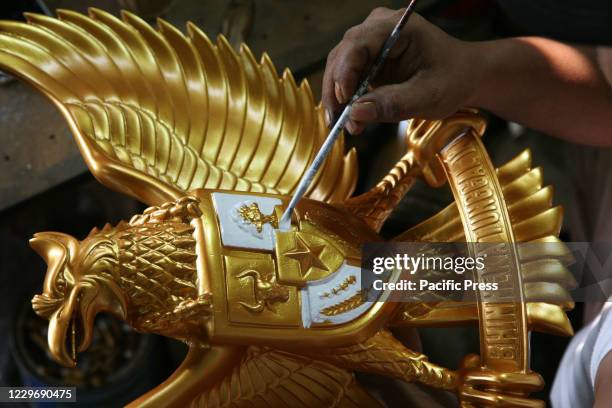 Worker finishing a fiberglass statue of the Garuda Pancasila emblem in a small factory enterprise in the Kalimalang area. Empowerment of Micro Small...