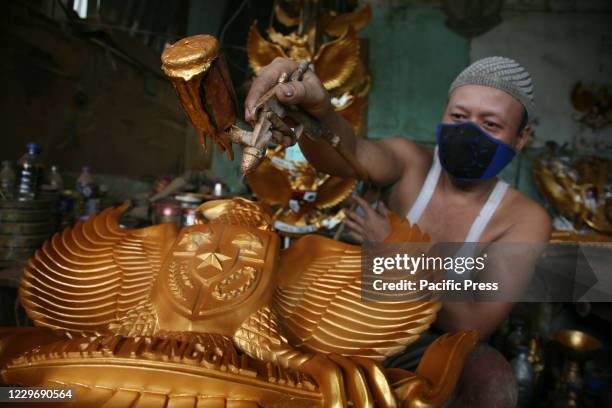 Worker wearing a face mask finishing a fiberglass statue of the Garuda Pancasila emblem in a small factory enterprise in the Kalimalang area....