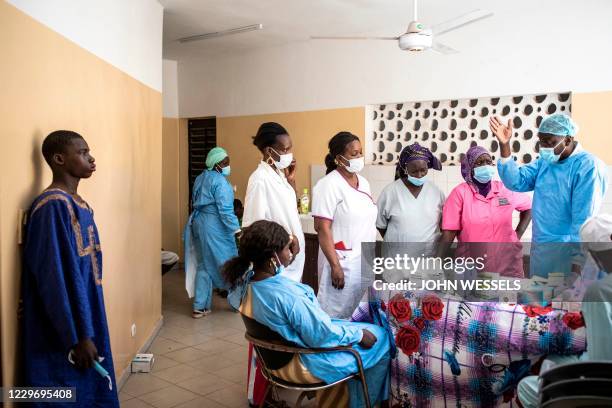 Doctors and nurses consult with each other as young fisherman waits to receive medical treatment for a mysterious skin disease in Dakar on November...