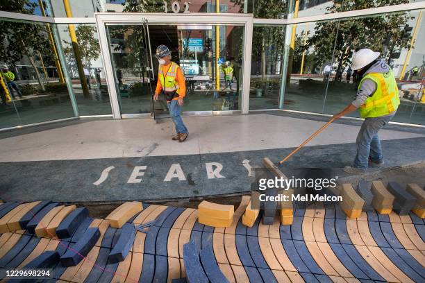 Cesar Villasenor, right, sweeps away dirt around the original sears logo located in front of the main entrance on Colorado Ave. To the vacant Sears...