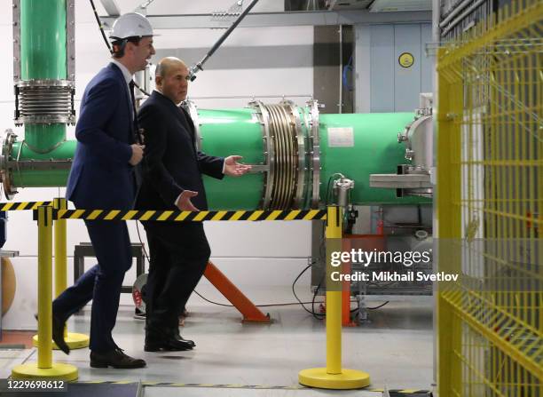 Russian Prime Minister Mikhail Mishustin listens to Grigory Trubnikov, the First Vice Director of the Joint Institute for Nuclear Research, while...