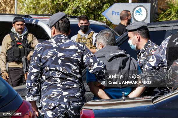 Policemen escort a prisoner who had fled a detention centre earlier upon recapture, in Baabda, east of Lebanon's capital Beirut, on November 21,...