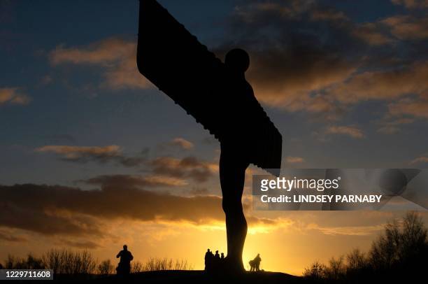 Visitors are pictured at the iconic 'Angel of the North' sculpture, designed by designed by British artist Antony Gormley, at sunset in Gateshead,...