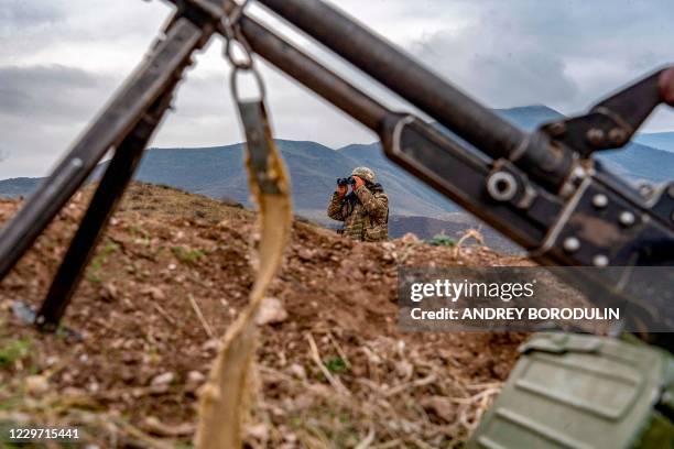 An Armenian soldier looks through binoculars during a patrol at the check point nearby a demarcation line outside Askeran on November 21 as...