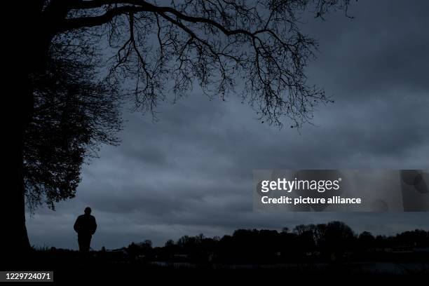 November 2020, Bremen: A man is walking along the dike. It's getting dark outside, winter's coming. Some people suffer more than others, the mood...