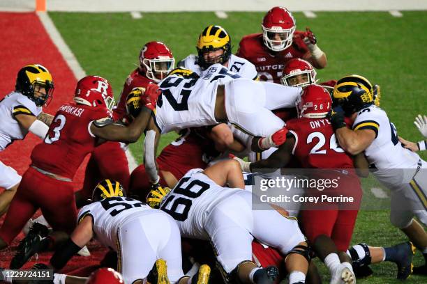 Hassan Haskins of the Michigan Wolverines leaps to score the final touchdown of the game against the Rutgers Scarlet Knights during triple overtime...