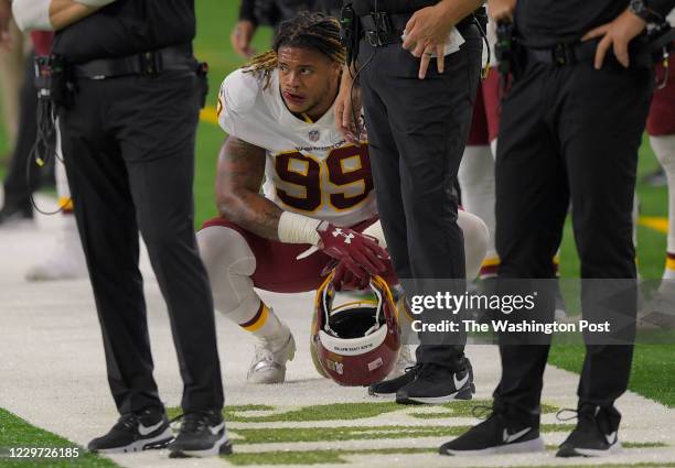 Washington Football Team defensive end Chase Young kneels and the feet of the coaches during a game between the Washington Football Team and the...