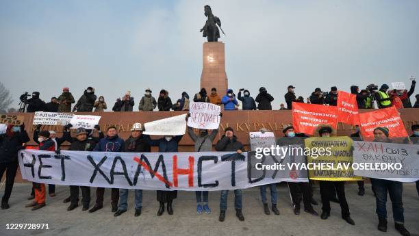 People hold placards as they attend a rally against the new constitutional amendments in Bishkek on November 22, 2020. - Hundreds took to the streets...