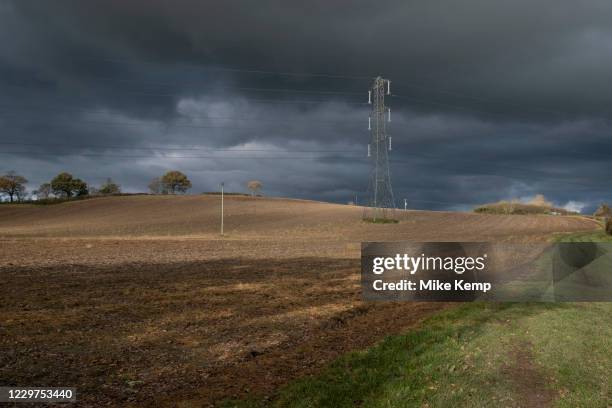 Power lines cross a prepared field in Warwickshire landscape on 10th November 2020 near Henley-in-Arden, United Kingdom.