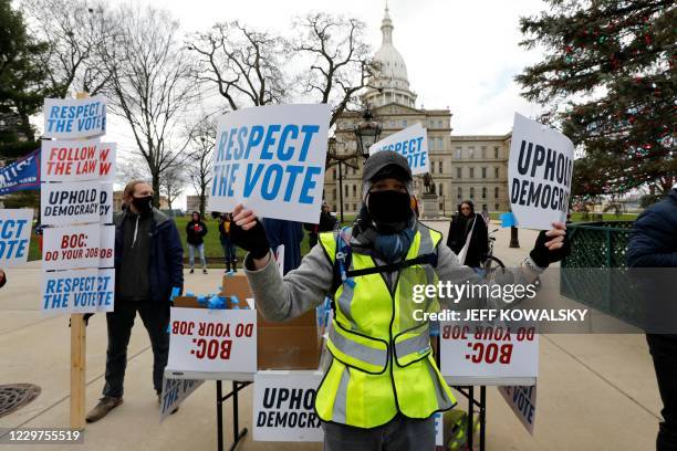 Supporters of US President-Elect Joe Biden stand in front of the Michigan State Capital as the Michigan Board of State Canvassers vote today to...
