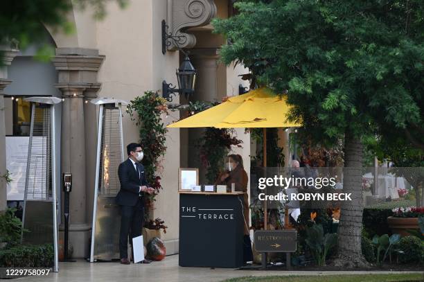 Restaurant hostess wearing a mask and face shields waits for customers at lunch time at a restaurant in Beverly Hills, California, November 23, 2020....