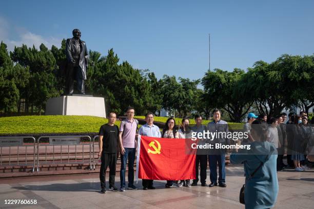 Group of visitors holding a Communist Party flag pose for a photograph in front of the statue of Deng Xiaoping at Lianhuashan Park in Shenzhen,...