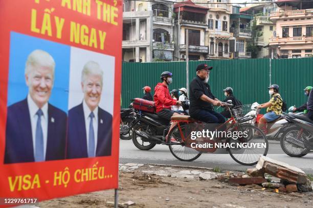 Man rides his bicycle past a billboard of a photo studio featuring an image of US President Donald Trump in Hanoi November 24, 2020.