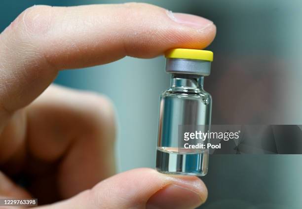 An employee holds an ampoule into which the vaccine is later filled as German Health Minister Jens Spahn tours the lab facilities of vaccine maker...
