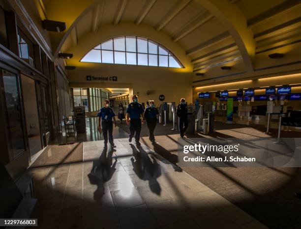 Transportation Security Administration agents are silhouetted by the afternoon sun as they make their way through John Wayne Airport for Thanksgiving...
