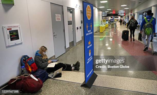 Bowdoin College student sits on the floor doing her homework on her way home to Portland Oregon in a social distancing atmosphere at Terminal B at...