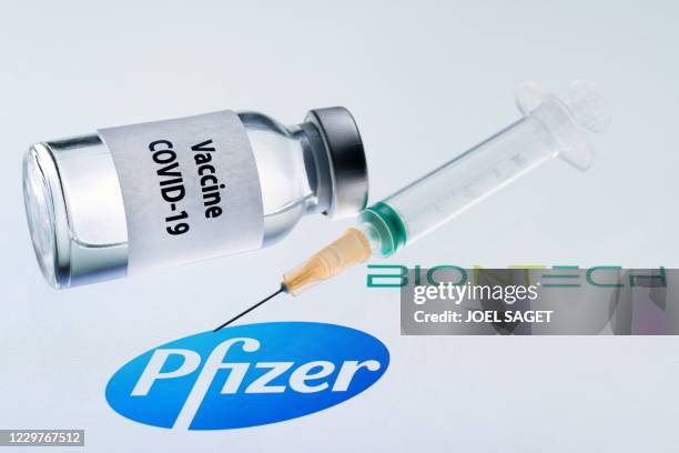 This illustration picture taken on November 23, 2020 shows a bottle reading "Vaccine Covid-19" and a syringe next to the Pfizer and Biontech logo. -...