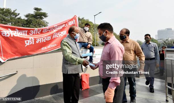 Leader Vijay Goel gives a facemask to a commuter during an awareness campaign on coronavirus outbreakat Connaught Place on November 24, 2020 in New...