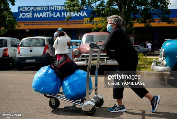 Cuban-American carries luggage as she leaves Havana's Jose Marti International Airport on November 20, 2020. - Used to avoiding difficulties and now...