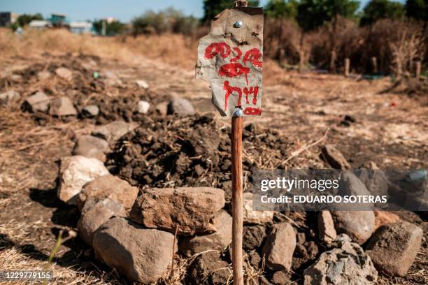 This photograph taken on November 21, 2020 shows an inscription on a sign at a collective grave in a cemetery, of victims that were allegedly killed...
