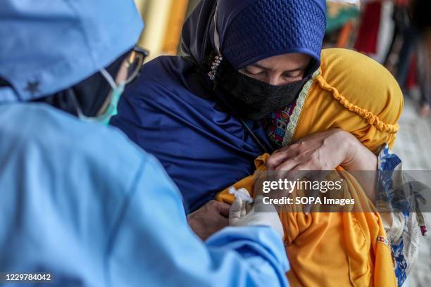 Health worker injecting a student during the immunization. School Health Immunization Program health workers inject tetanus diphtheria vaccine to...