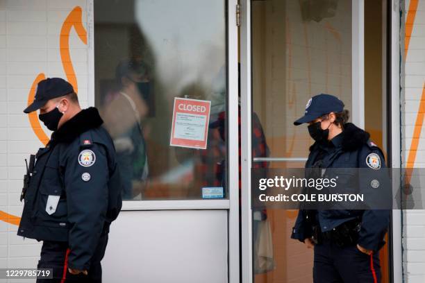 Toronto Police officers walk by a shutdown order on the window of Adamson Barbecue, an Etobicoke business that has defied provincial shutdown orders,...