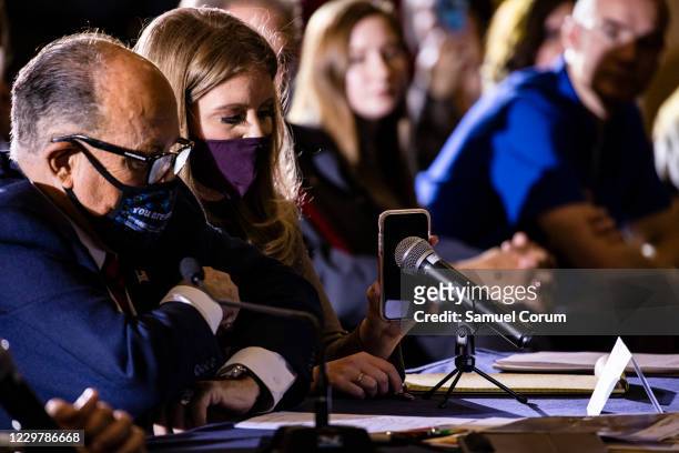 Jenna Ellis, a member of President Donald Trumps legal team, holds up a cell phone to the microphone so President Trump can speak during a...