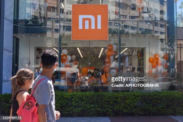People walk pass by the the Xiaomi store front during the inauguration of the Xiaomi store on November 25, 2020 in San Salvador, El Salvador. The...