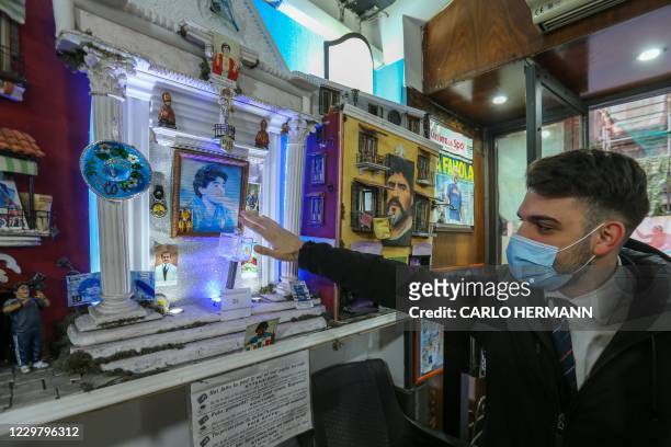 Man places his hand over a box purportedly containing a lock of Diego Maradona's hair, at a small altar dedicated to Argentinian football legend...