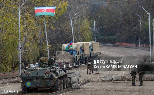 Russian APC and soldiers of the peacekeeping force patrol in front of an Azerbaijan's army checkpoint near the demarcation line outside the town of...