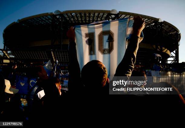 Man holds a jersey of Argentina's national football team with Diego Maradona's number 10 as people gather outside the San Paolo stadium in Naples on...