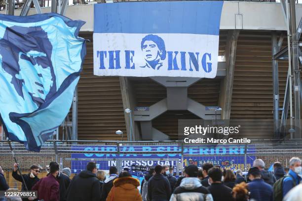 Fan of Diego Armando Maradona waves a flag with the footballer's face in front of the San Paolo stadium in Naples, with a giant banner, the day after...