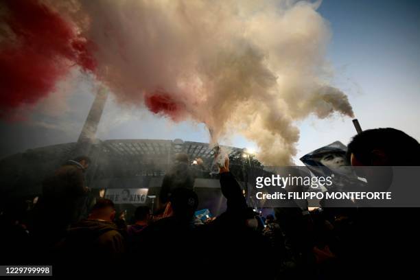Fans light flare bombs as people gather outside the San Paolo stadium in Naples on November 26, 2020 to mourn the death of late Argentinian football...