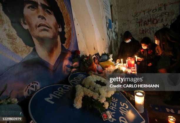 Youth light candles to mourn the death of Argentinian football legend Diego Maradona, on November 26, 2020 at a makeshift altar set up in the...