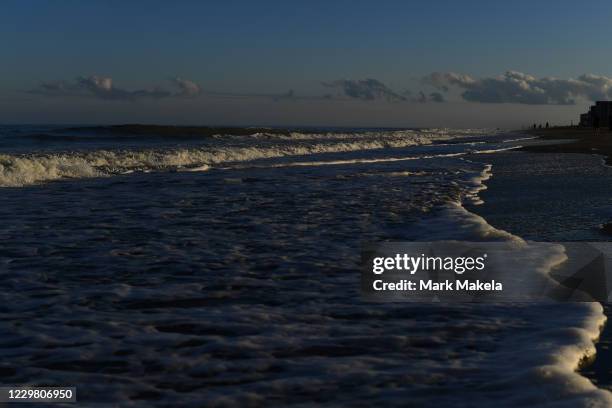 Dusk light illuminates the ocean surf as beachgoers enjoy an unseasonably warm 70 degree Thanksgiving day on November 26, 2020 in Rehoboth Beach,...