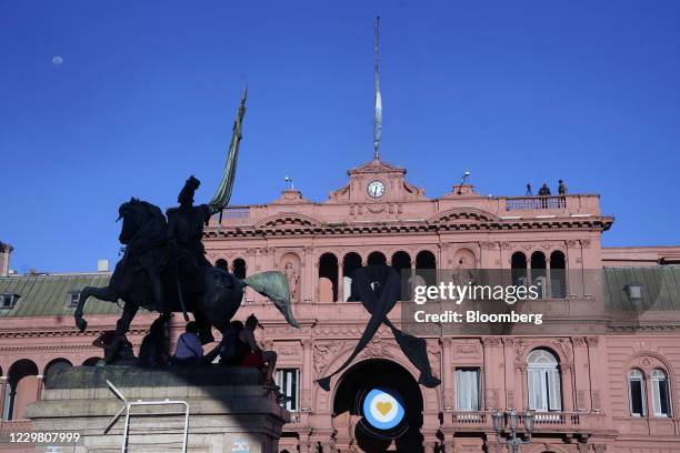 People sit under the equestrian monument to General Manuel Belgrano during a tribute to the late Argentine football star Diego Maradona, outside the...