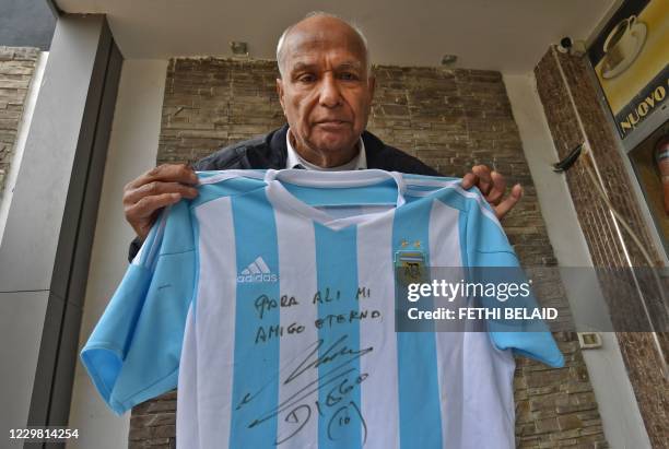 Tunisian referee Ali Bin Nasser poses at home in the capital Tunis on November 27 with the shirt given to him by Diego Armando Maradona when he...