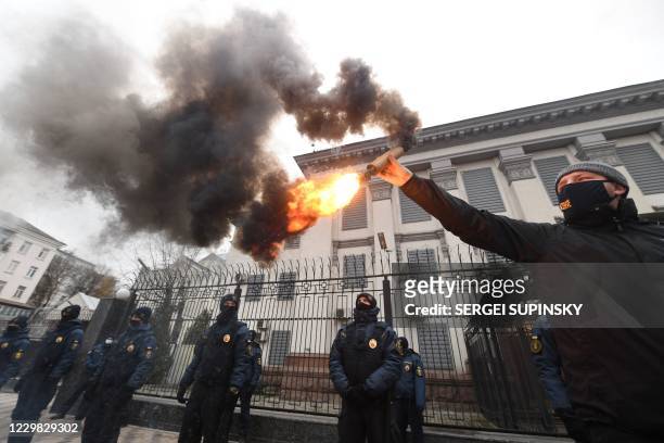 Ukrainian far-right activists burn smog bombs outside Russian embassy in Kiev on November 28, 2020 during their protest action called "You killed us...