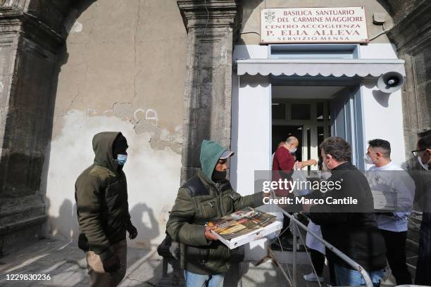 People queuing in front of the Caritas in Carmine square in Naples, while they receive a meal and pizza, during the Pizza Solidale initiative, the...