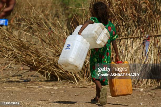 An Ethiopian refugee girl walks carrying water containers at Um Raquba camp in Sudan's eastern Gedaref state on November 28, 2020. - Sudan needs $150...