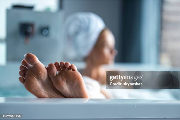 fermez-vous vers le haut des pieds de la femme dans le bain moussant. - se faire dorloter photos et images de collection