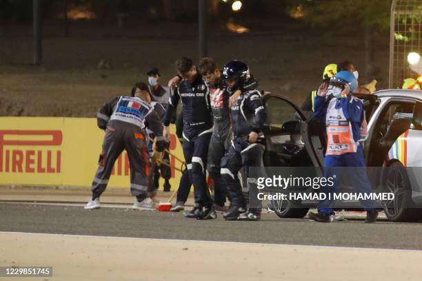 Stewards and medics attend to Haas F1's French driver Romain Grosjean after a crash at the start of the Bahrain Formula One Grand Prix at the Bahrain...