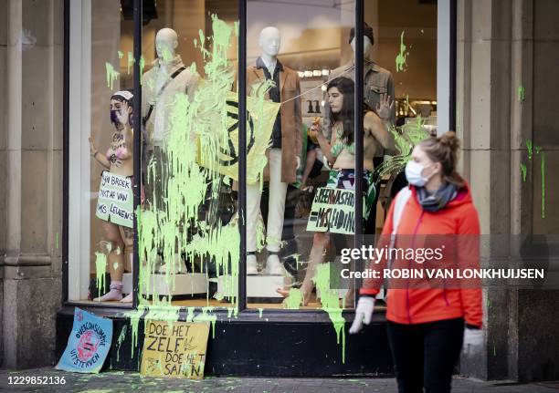 Activists of the group Extinction Rebellion stand in an H&M clothes store window on November 29, 2020 in Amsterdam to denounce the alledged...