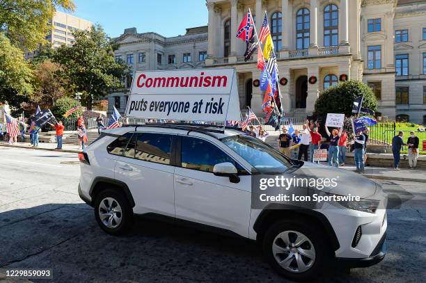 Car with a sign referencing Communism drives by Trump supporters at a Stop The Steal rally in front of the Georgia State Capitol Building on November...