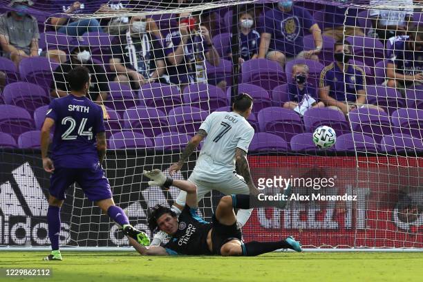 Gustavo Bou of New England Revolution scores a goal past Brian Rowe of Orlando City SC and Kyle Smith of Orlando City SC during the MLS Eastern...