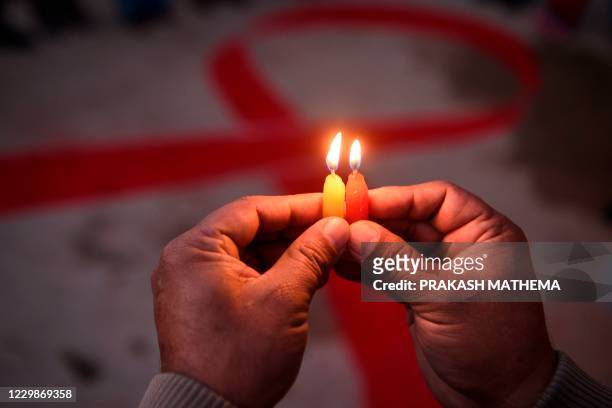 Volunteer lights candles forming the shape of a red ribbon during an awareness event on the eve of the World AIDS Day, in Kathmandu on November 30,...